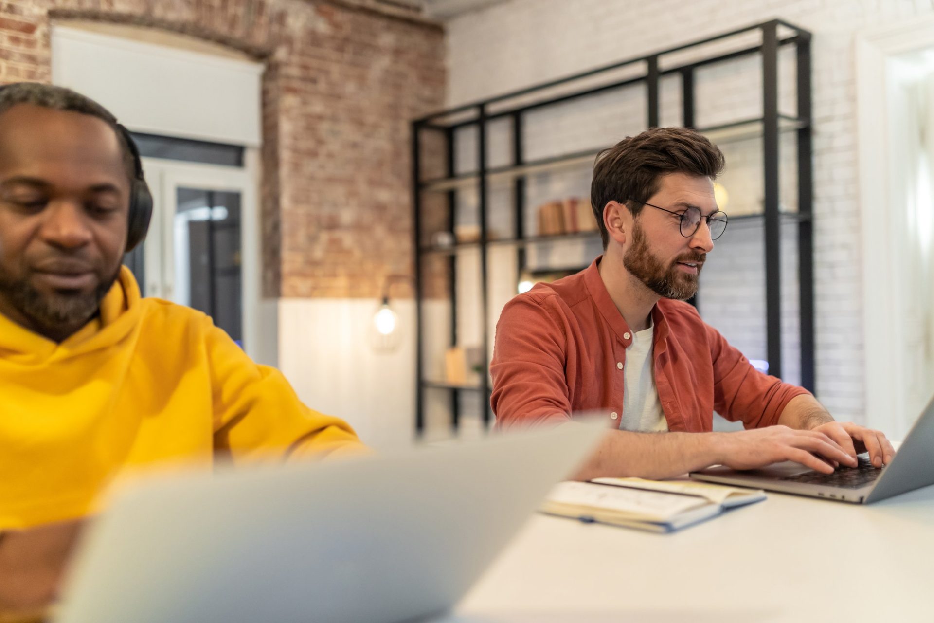 Two business owners working side by side on laptops in a bright office